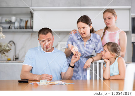 Dissatisfied husband and father give out pocket money to wife and children in kitchen Dissatisfied husband and father give out pocket money to wife and children in kitchen 130542817