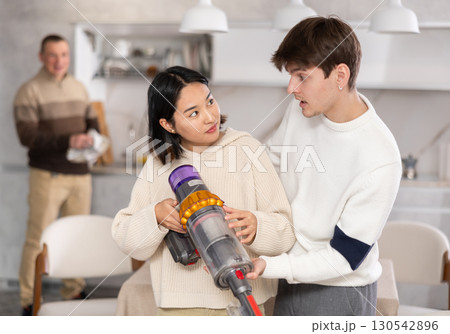 Young guy and young woman vacuuming floor 130542896