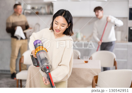 Young woman vacuuming kitchen floor Young woman vacuuming kitchen floor 130542951
