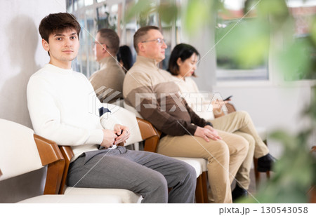 Young guy sits in line at reception Young guy sits in line at reception 130543058