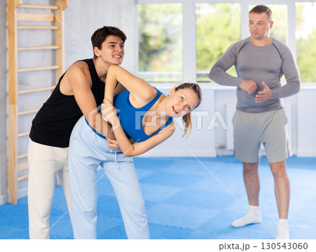 Guy and woman train to perform defense of strangling opponent, while learning self-defense Guy and woman train to perform defense of strangling opponent, while learning self-defense 130543060