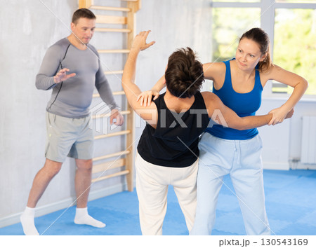Guy and woman train to perform defense of strangling opponent, while learning self-defense 130543169