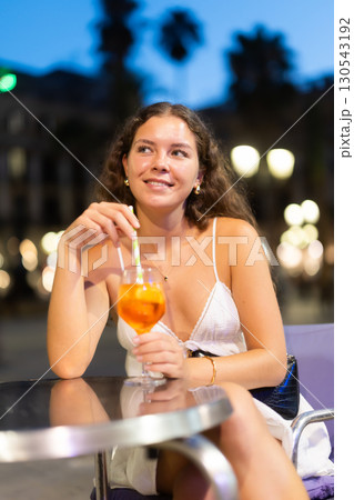 Young woman with a cocktail in her hands is sitting in the square Young woman with a cocktail in her hands is sitting in the square 130543192