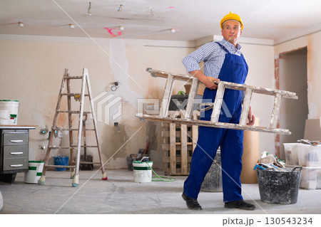 Man builder carrying stepladder 130543234