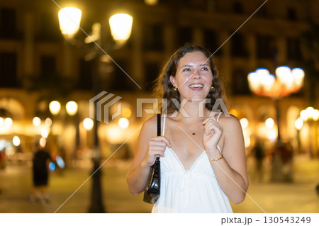In night, young smiling girl walks along city street Placa Real 130543249