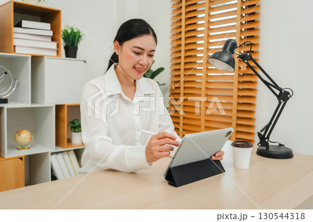 happy woman working with digital tablet at home office 130544318