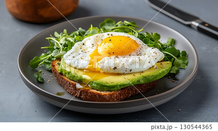 Delicious Poached Egg on Avocado Toast with Fresh Greens and Olive Oil Drizzle Delicious Poached Egg on Avocado Toast with Fresh Greens and Olive Oil Drizzle 130544365
