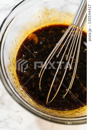 A top-down view of dark molasses and two eggs in a glass bowl, part of the wet ingredients for Zesty Orange Gingerbread Cookie Dough. The molasses adds depth and a rich color to the gingerbread. A top-down view of dark molasses and two eggs in a glass bowl, part of the wet ingredients for Zesty Orange Gingerbread Cookie Dough. The molasses adds depth and a rich color to the gingerbread. 130544417