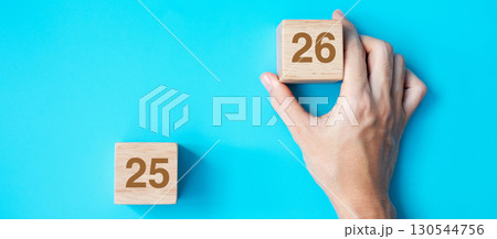 hand holding wooden cube block with 2026 text on blue background. Resolution, plan, review, goal, start and New Year holiday concepts 130544756