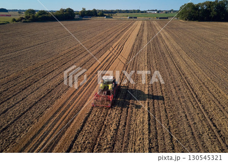Tractor working on agricultural field, plowed farmland 130545321