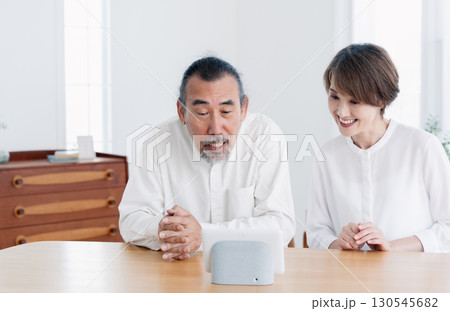 リビングでスマートスピーカに話しかけるシニア夫婦 130545682