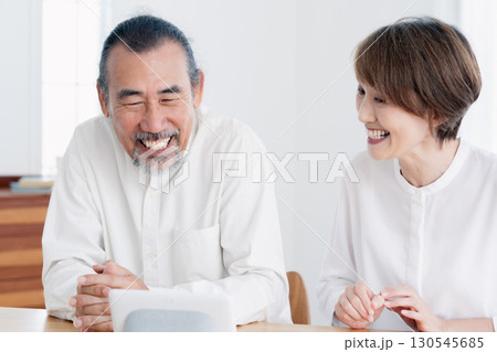 リビングでスマートスピーカに話しかけるシニア夫婦 130545685