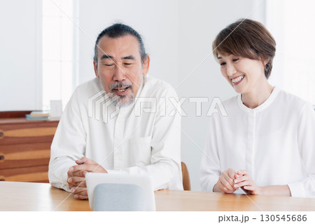 リビングでスマートスピーカに話しかけるシニア夫婦 リビングでスマートスピーカに話しかけるシニア夫婦 130545686
