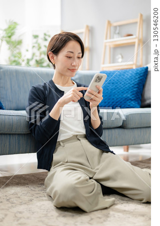 リビングでスマホを使う女性 130546200