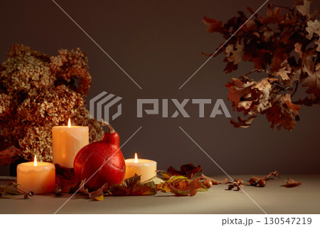 Still life with pumpkin, dried-up leaves, and burning candles. 130547219