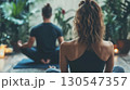 Back view of young couple practicing yoga together at home in living room 130547357