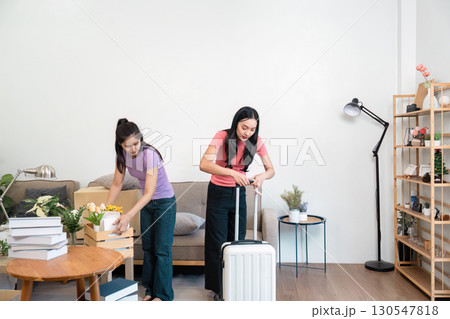 LGBTQ couple unpacking their luggage and boxes in their new home, embracing the excitement of settling into their shared space. 130547818