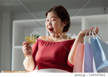 Excited woman shopping with credit card and colorful bags 130547852