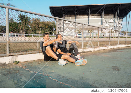 Relaxed elderly men taking a break and hydrating after a workout on the track. Highlighting friendship, wellness, and active aging. Relaxed elderly men taking a break and hydrating after a workout on the track. Highlighting friendship, wellness, and active aging. 130547901