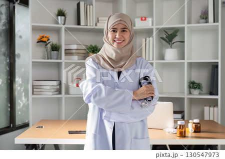 Confident Muslim female doctor posing with stethoscope in a modern healthcare office, showcasing diversity and professionalism. Confident Muslim female doctor posing with stethoscope in a modern healthcare office, showcasing diversity and professionalism. 130547973
