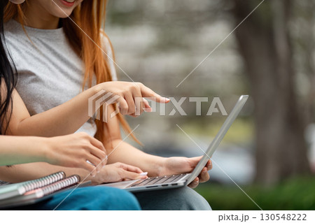 Students collaborating and engaging with a laptop in a vibrant outdoor setting Students collaborating and engaging with a laptop in a vibrant outdoor setting 130548222