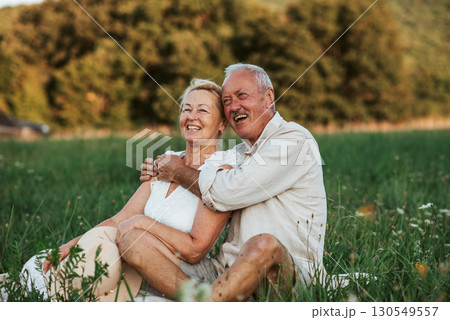 Happy senior couple embracing in meadow at sunset. Happy senior couple embracing in meadow at sunset. 130549557