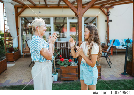 Grandmother and granddaughter playing clapping game. 130549606