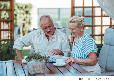Senior couple looking at family photo album together. Senior couple looking at family photo album together. 130549621