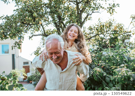 Grandfather playing with granddaughter in the garden. 130549622