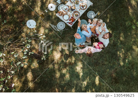 Drone shot of grandparents, parents and children hugging in circle at family celebration 130549625