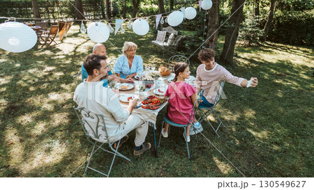 Family gathering for barbecue in summer garden, taking selfie. 130549627