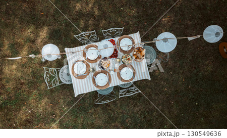 Rustic garden table prepared for summer party, aerial perspective. Rustic garden table prepared for summer party, aerial perspective. 130549636