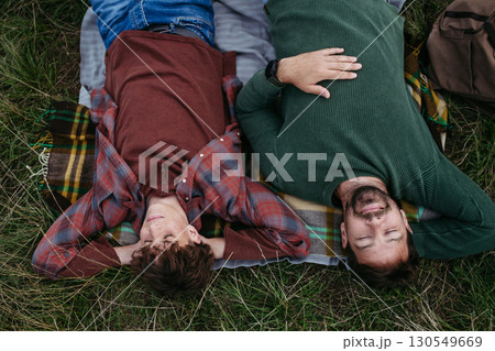 Top view of father and teen boy lying in grass and resting during hiking trip. 130549669