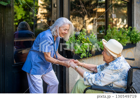 Tender moment between older caregiver and senior female patient in wheelchair. Tender moment between older caregiver and senior female patient in wheelchair. 130549719