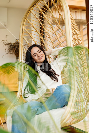 Relaxed woman taking a break, sitting in hanging chair. Relaxed woman taking a break, sitting in hanging chair. 130549817
