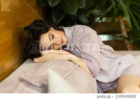 Depressed woman with hair rollers sitting on sofa and thinkiing. Depressed woman with hair rollers sitting on sofa and thinkiing. 130549892