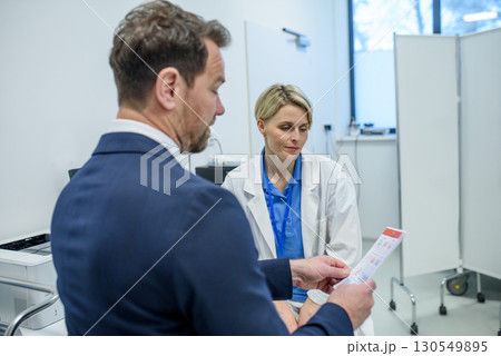 Pharmaceutical sales representative introducing new medication to female doctor. 130549895