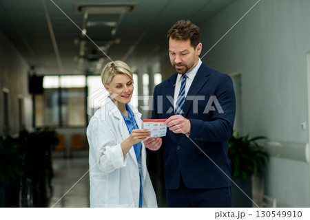 Pharmaceutical sales representative introducing new medication to female doctor. Pharmaceutical sales representative introducing new medication to female doctor. 130549910