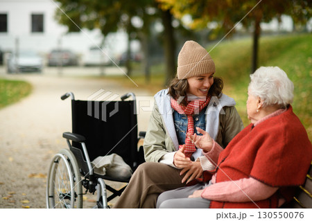 Granddaughter talking grandmother in autumn park. 130550076