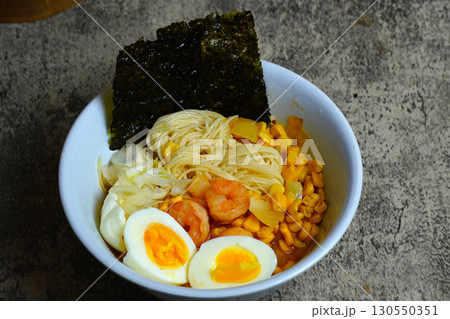 Shrimp ramen with boiled egg, corn, and nori. A delicious and savory Asian noodle soup, perfect for a hearty meal. 130550351