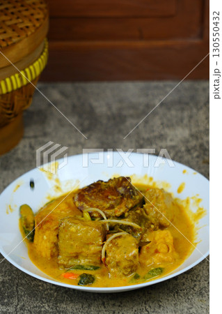 Authentic Ikan Pe, a traditional Indonesian dish from Surabaya, East Java. Smoked stingray curry with rice cake, tofu, and vegetables in rich coconut milk. 130550432