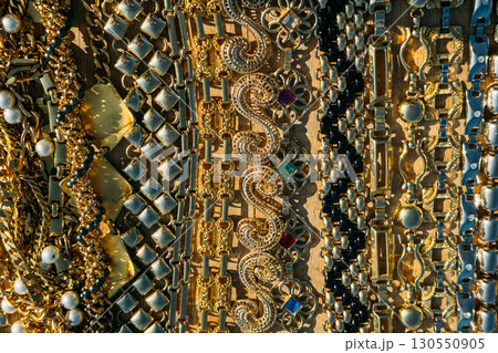 Close-up view of ornate vintage gold chain bracelets arranged in parallel rows on wood. Sustainable glam, reused beauty, vintage jewelry, zero-waste style 130550905