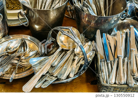 A collection of silver cutlery including knives, forks, and spoons arranged in baskets and trays. Secondhand cutlery, vintage flatware, elegant dining revival, heirloom tableware A collection of silver cutlery including knives, forks, and spoons arranged in baskets and trays. Secondhand cutlery, vintage flatware, elegant dining revival, heirloom tableware 130550912