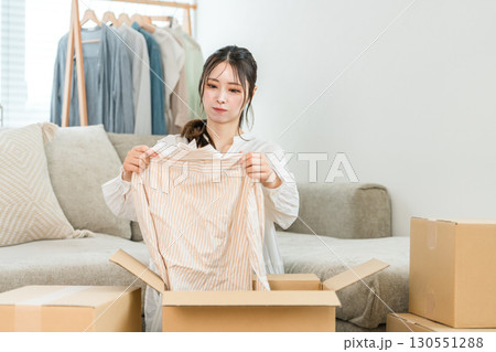 家で不用品整理,処分,断捨離,片付け,服を捨てる若い女性 130551288