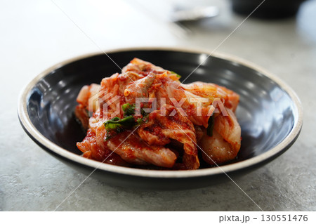 Closeup of Spicy Kimchi Korean Fermented Cabbage Dish in Black Bowl Closeup of Spicy Kimchi Korean Fermented Cabbage Dish in Black Bowl 130551476