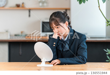 家のリビングで鏡を見ながら落ち込む制服姿の小学生,中学生の女の子（コンプレックス,トラブル） 130551944