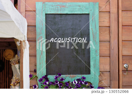 Copy space. Attraction of investments concept. ACQUISITION word written on Charming wooden wall with a turquoise-framed chalkboard Copy space. Attraction of investments concept. ACQUISITION word written on Charming wooden wall with a turquoise-framed chalkboard 130552066