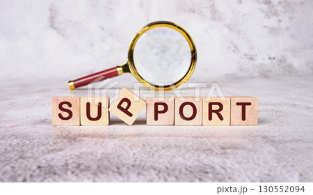 The concept word SUPPORT has been collected of wooden cubes with a magnifying glass in the background. Business and SUPPORT concept. Copy space 130552094