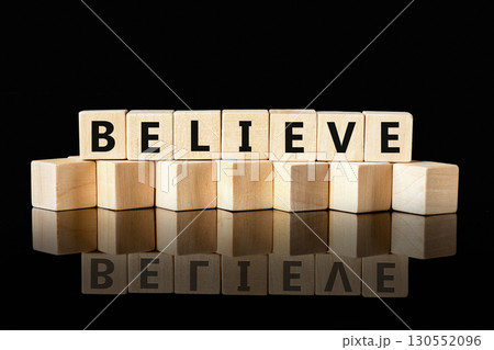 The concept word BELIEVE has been collected of wooden cubes on a glossy black background. Business believe concept. Copy space. The concept word BELIEVE has been collected of wooden cubes on a glossy black background. Business believe concept. Copy space. 130552096