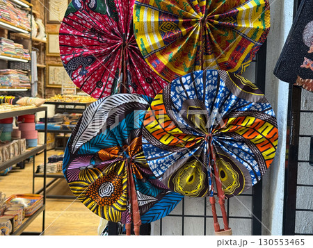 Colorful handmade fabric fans on display in a souvenir shop. Cultural heritage, artisan craft, and vibrant textile tradition symbolizing identity and creativity. Colorful handmade fabric fans on display in a souvenir shop. Cultural heritage, artisan craft, and vibrant textile tradition symbolizing identity and creativity. 130553465